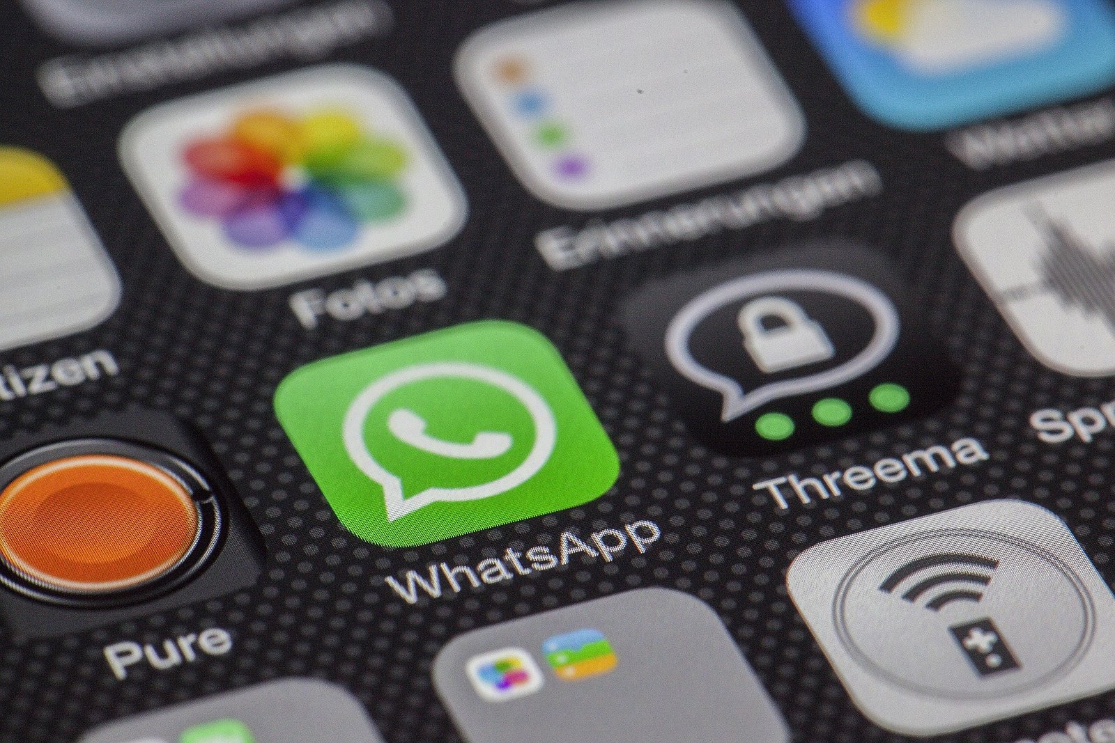 A close-up of a cell phone screen showing a variety of apps, including WhatsApp, Fotos, Chrome, and Spotify. There is also a search bar at the top of the screen.