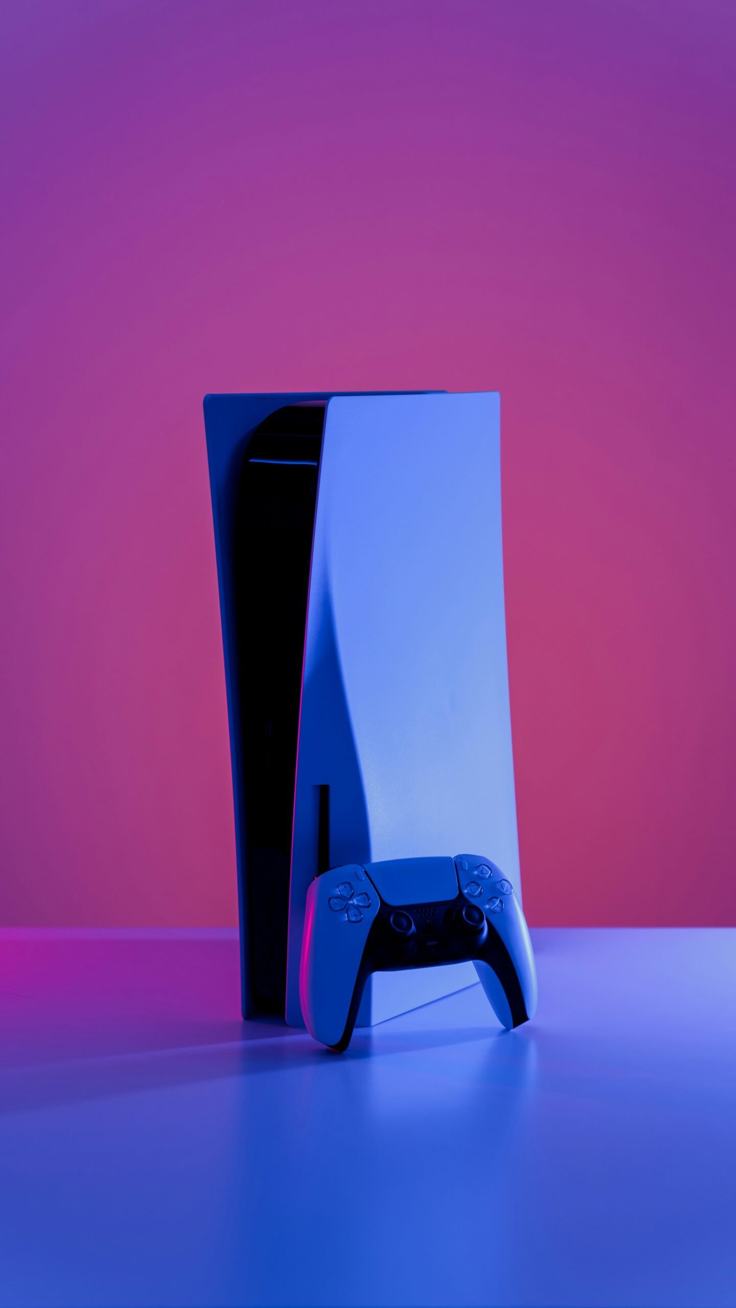 Sony PS5 Console - $100 Price Hike Coming This April Sony PlayStation 5 disc console and DualSense controller bathed in neon purple and blue lighting, highlighting the upcoming $100 PS5 price increase in April.